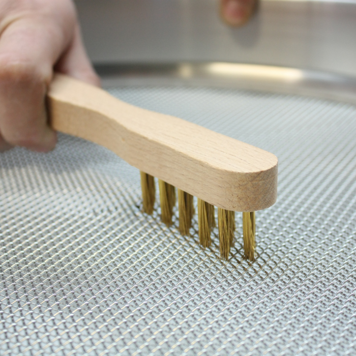 utilisation d'une brosse en laiton pour nettoyer un tamis